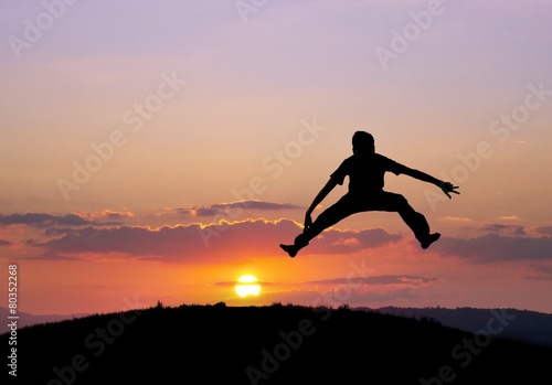 silhouetted boy jumping in sunset