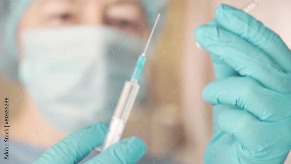 Female doctor carefully preparing an injection Female doctor carefully preparing an injection