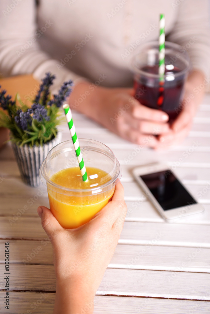 Two female hands with fast food cups of juice and mobile phone Two female hands with fast food cups of juice and mobile phone