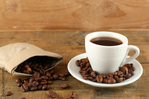 Cup of coffee with beans on rustic wooden background