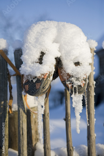 old shoes hanging on a fence in winter in a russian village