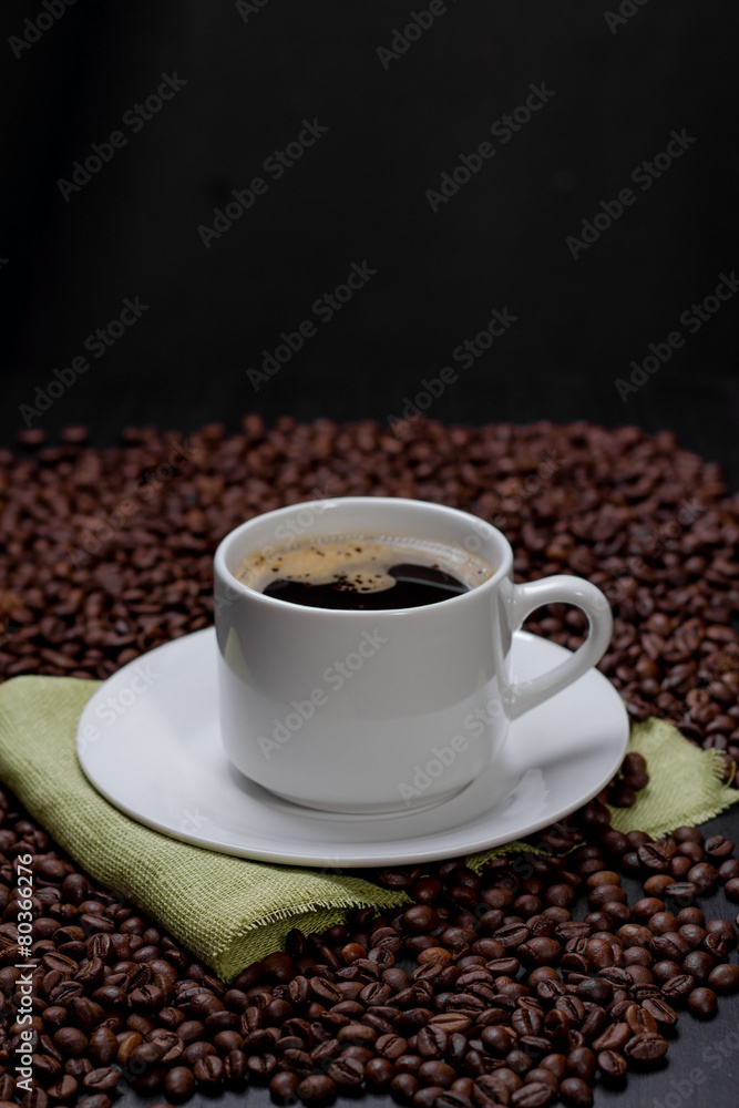 Naklejka premium Coffee cup and saucer and coffee beans. Dark background.