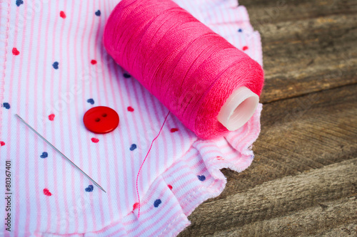 Pink threads, buttons and needles on fabric photo