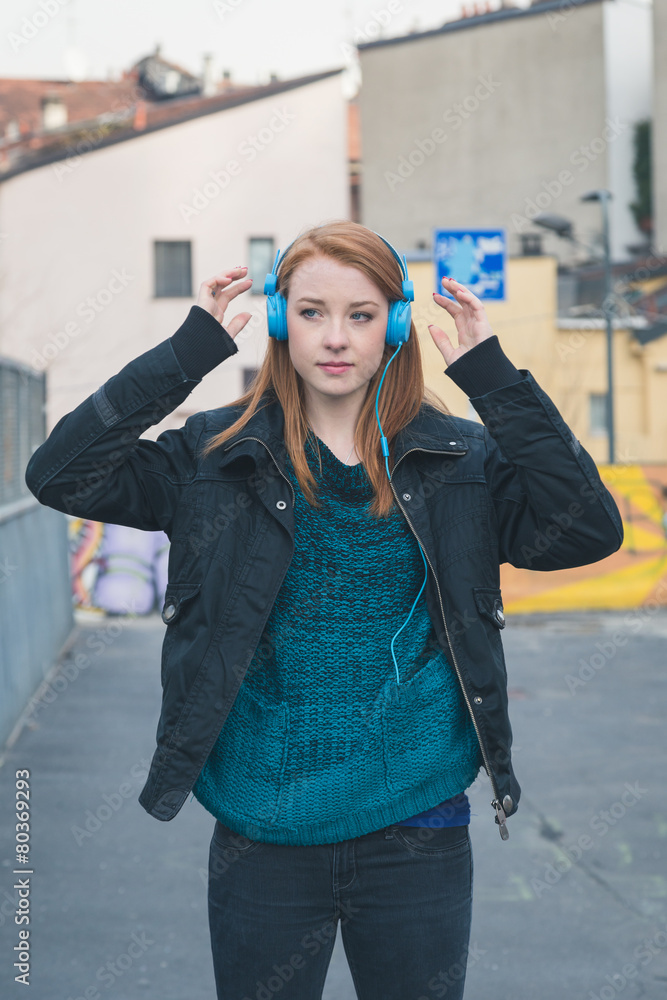 Beautiful girl with headphones posing in the city streets