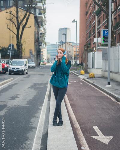 Beautiful girl listening to music in the city streets