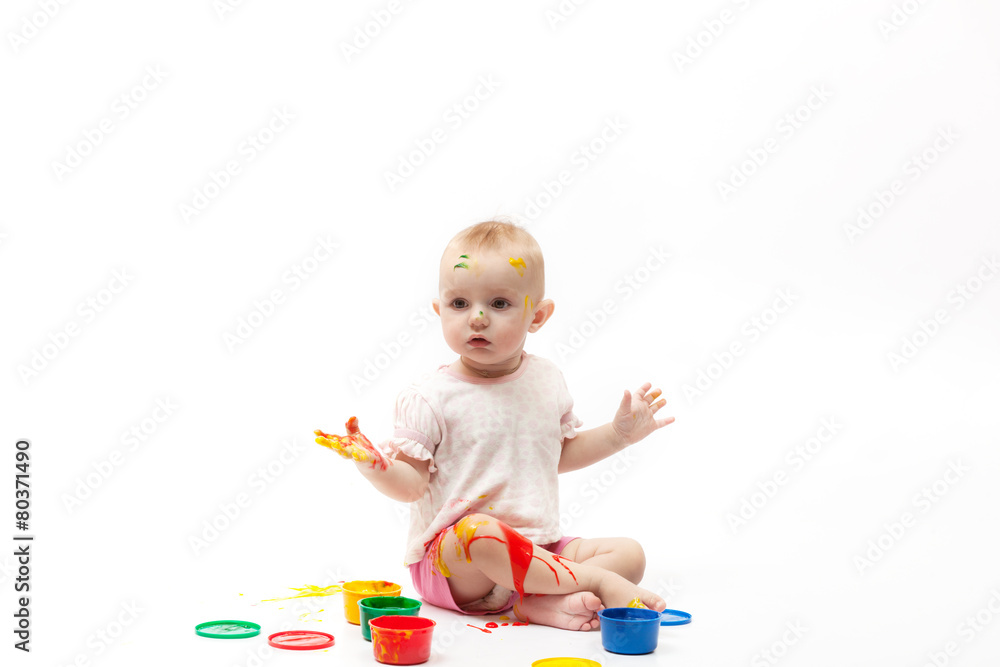 surprised child soiled by multi-colored paints sits surprised child soiled by multi-colored paints sits