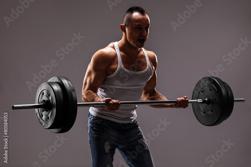 Strong muscular man lifting a heavy barbell