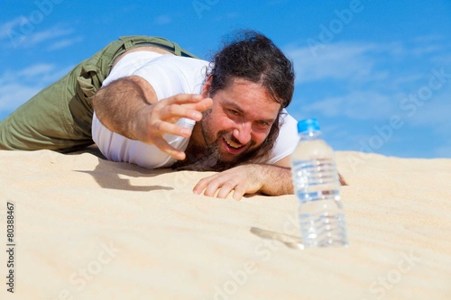 thirsty man reaches for a bottle of water in the empty photo