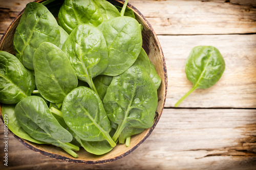 Spinach on the bowl, wooden background.