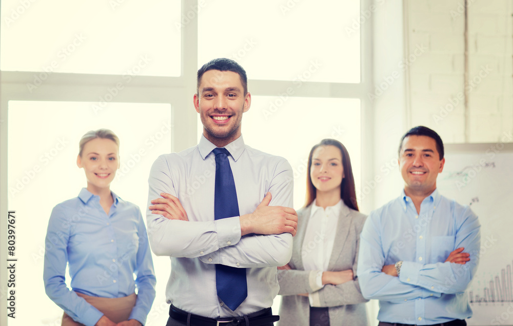 smiling businessman in office with team on back smiling businessman in office with team on back