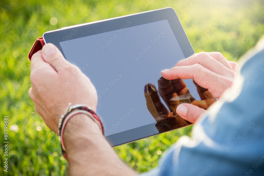 Adult man using a digital tablet at the park - obrazy, fototapety, plakaty 