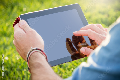 Adult man using a digital tablet at the park