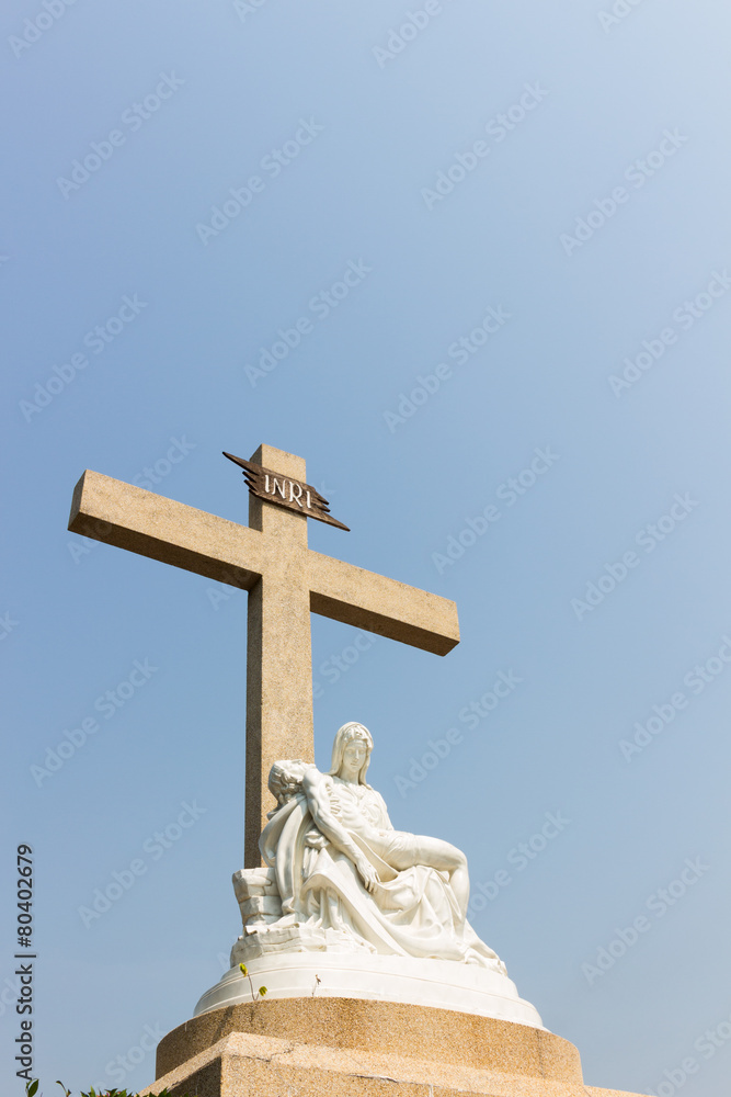 Pieta statue with cross and sky background