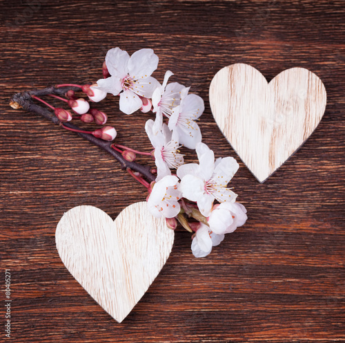 Two wooden hearts with spring cherry blossom flowers on a vinta