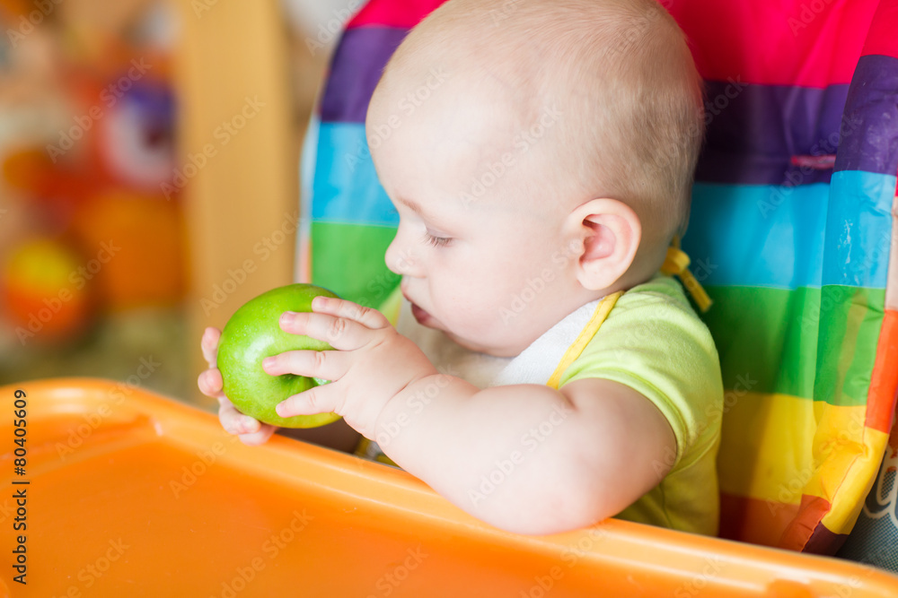 Adorable baby eating apple in high chair Adorable baby eating apple in high chair