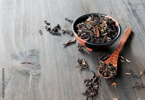 bowl with black tea and spoon on a wooden