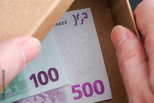 Hands open box with Euro banknotes in it