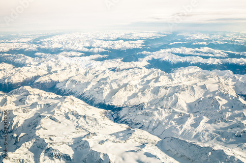 Aerial view of italian Alps with snow and misty horizon