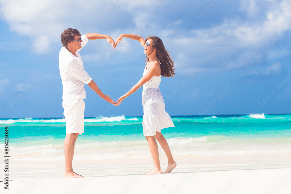 young happy couple in white making heart shape on tropical beach young happy couple in white making heart shape on tropical beach