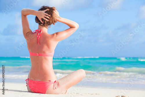 back view of long haired woman in bikini on tropical beach