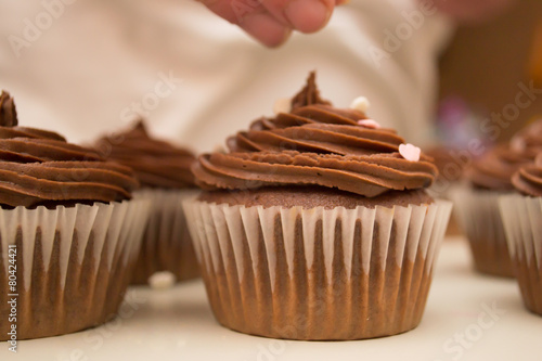 Chocolate cupcake getting sprinkles
