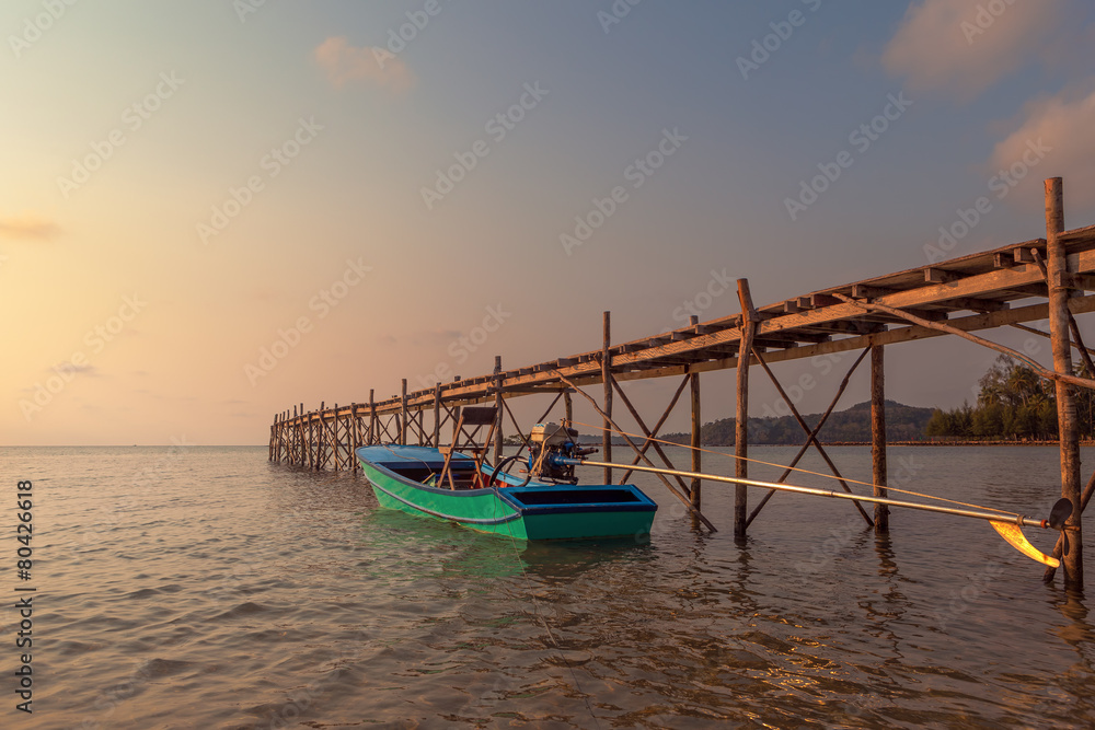Sunset over the beautiful tropical beach with bridge and boat