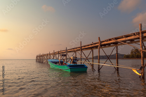 Sunset over the beautiful tropical beach with bridge and boat