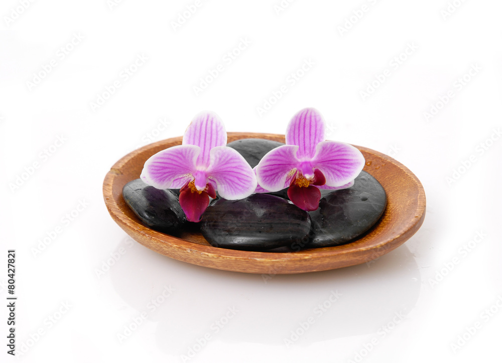 Fototapeta premium Two pink orchid with black stones on wooden bowl