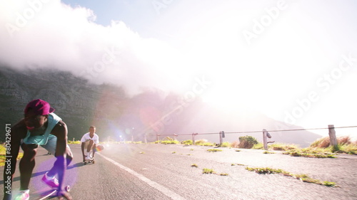 Skater girl downhill racing on her longboard with friends photo