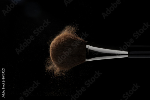 Horizontal makeup brush in motion on black background
