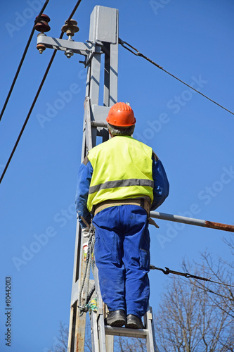 Electrician is working next to an electricity pylon