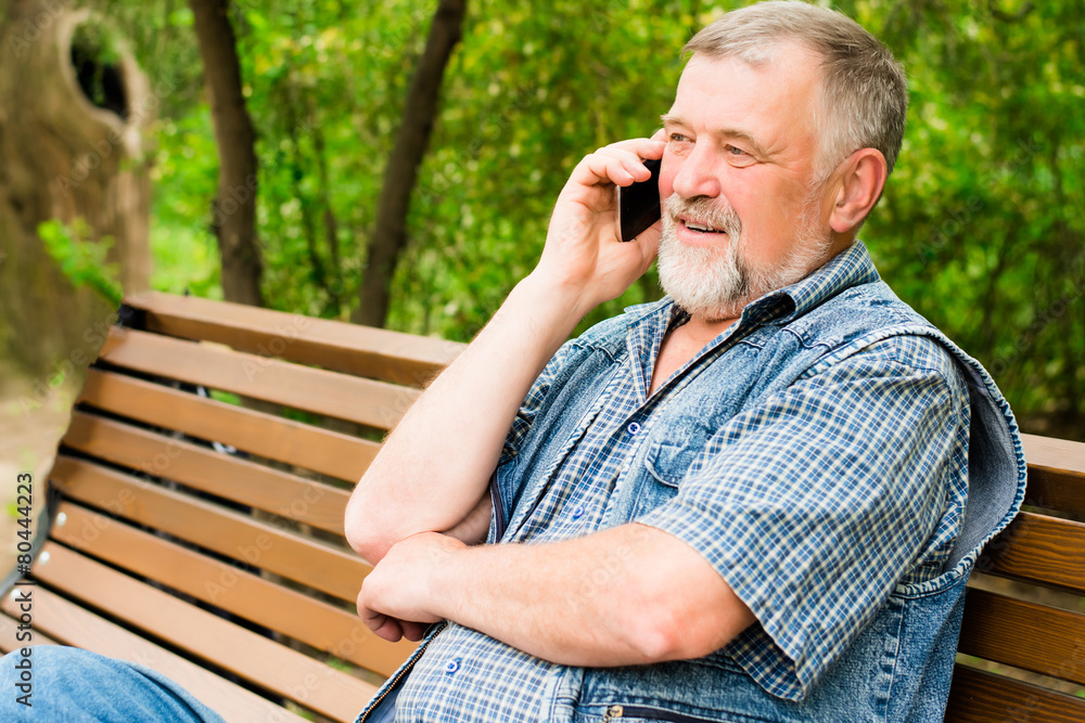 Fototapeta premium old man on a park bench talking on the phone