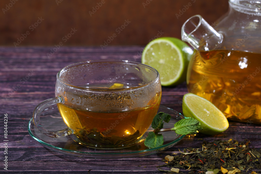 Tea in a glass teapot and a transparent cup with lime and mint o Tea in a glass teapot and a transparent cup with lime and mint o