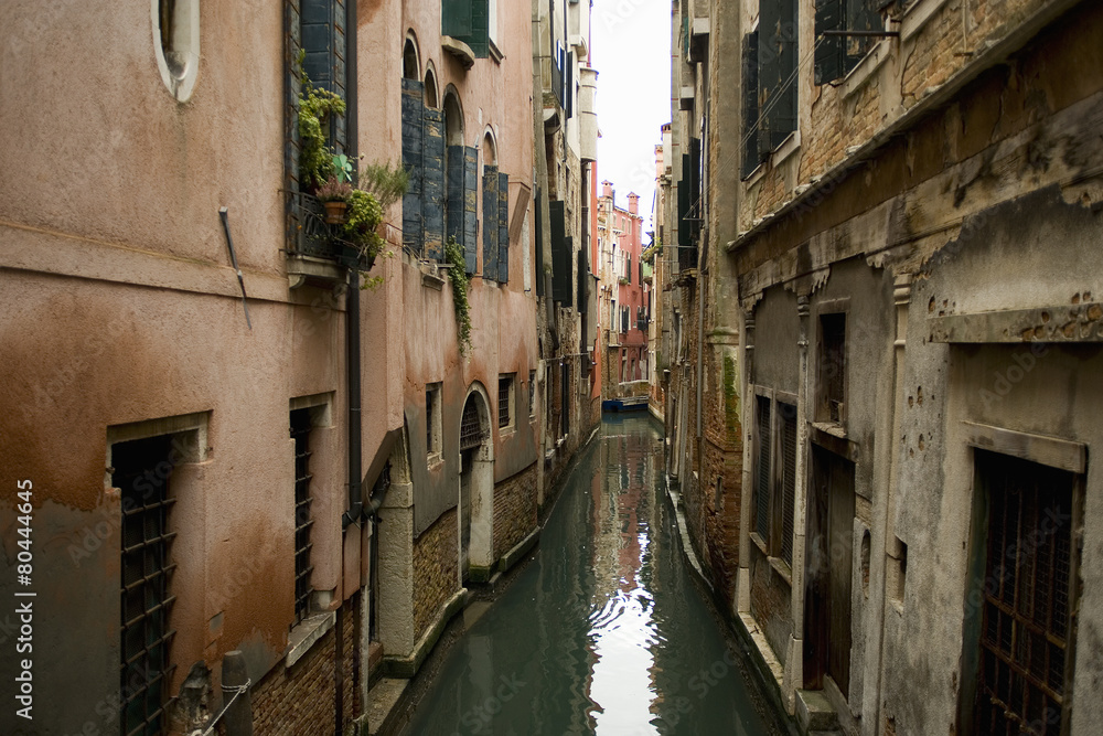 A view from above of a quiet backwater, a narrow canal with historic buildings rising from the water. A view from above of a quiet backwater, a narrow canal with historic buildings rising from the water.
