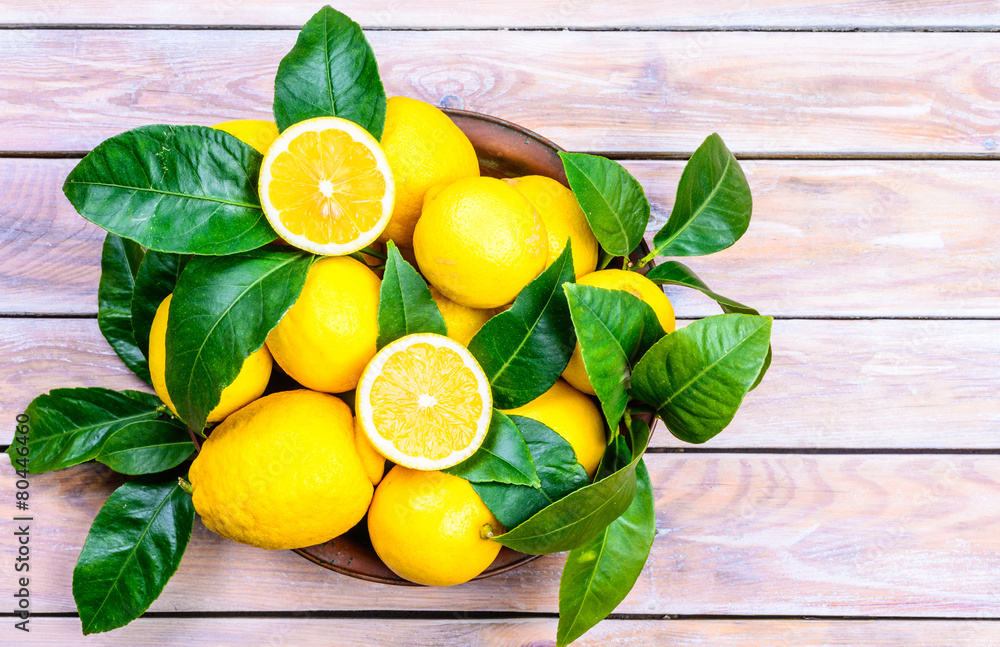 Naklejka Lemons with leaves on rustic wood background.Citrus fruits.