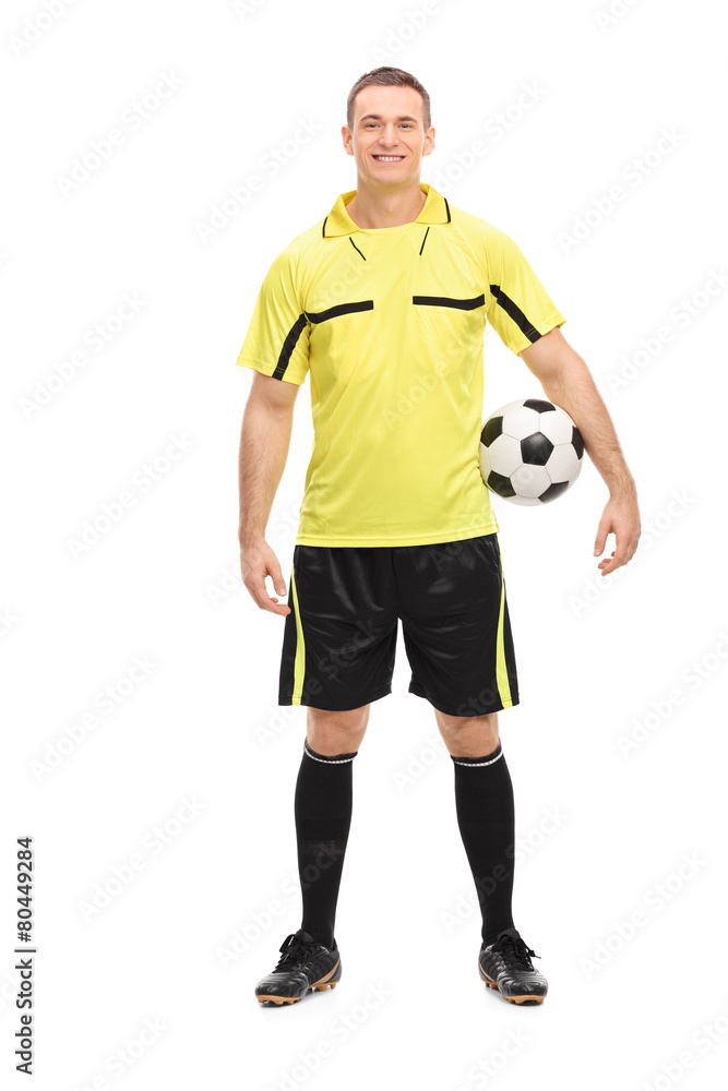 Football referee in a yellow jersey holding a ball
