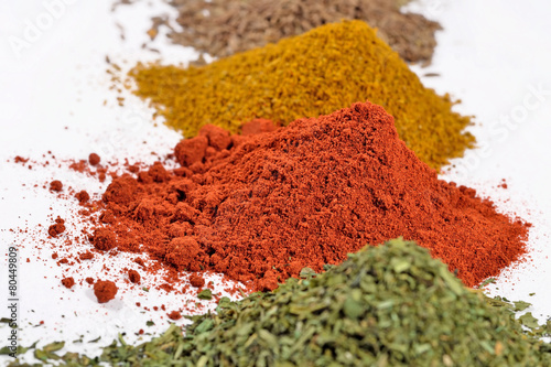 Heaps of different dry spices on a white