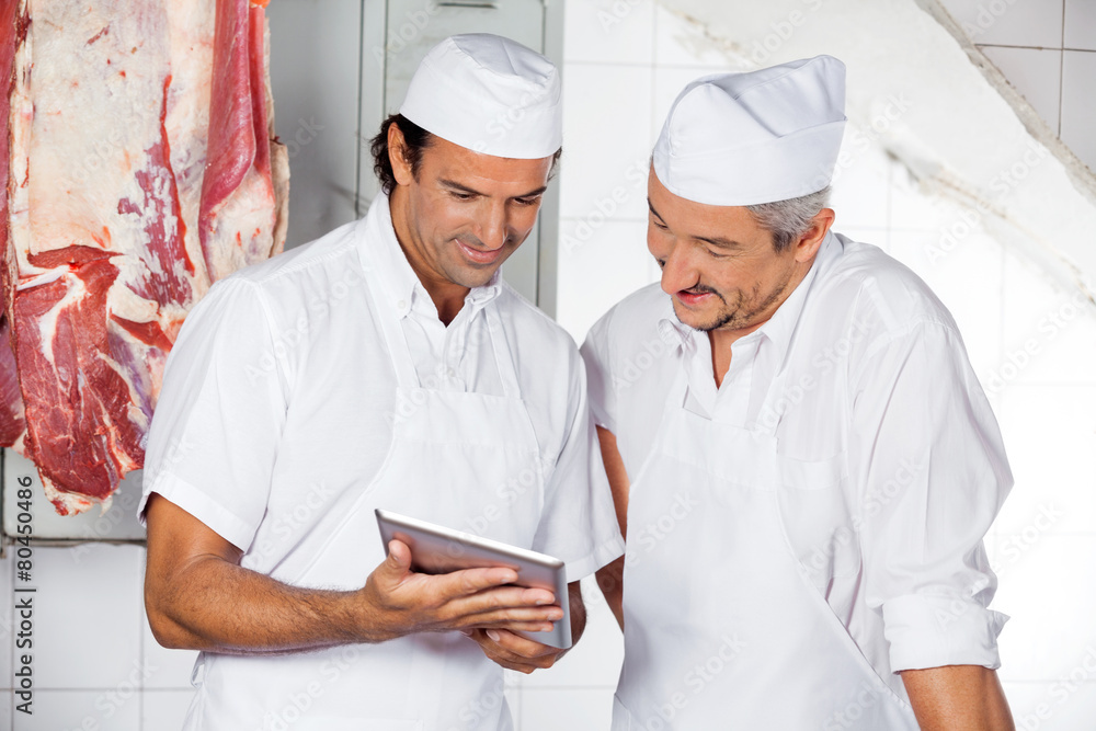 Butchers Using Digital Tablet In Butchery