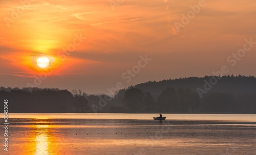 Sunset lake with fisherman boat landscape.