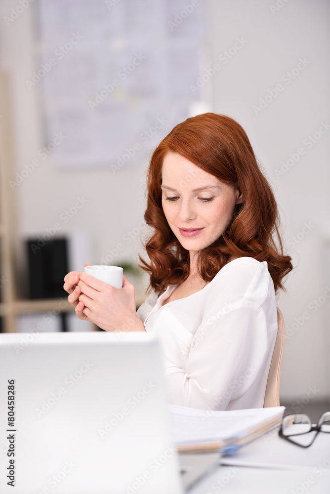 sympathische frau am schreibtisch mit einer tasse tee