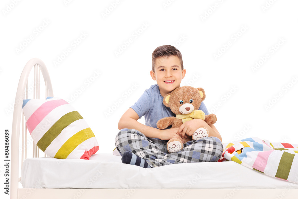 Happy little boy sitting in bed and hugging a teddy bear Happy little boy sitting in bed and hugging a teddy bear