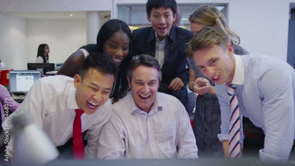 Happy business group looking at computer screen are pleased with their success Happy business group looking at computer screen are pleased with their success
