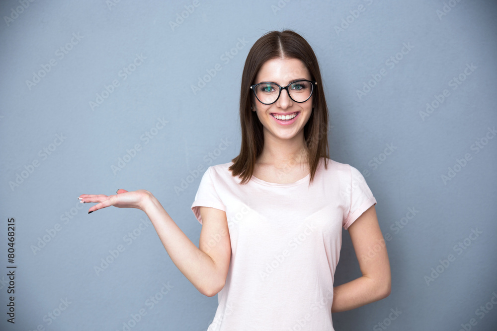 Happy young woman in glasses presenting something on the hand