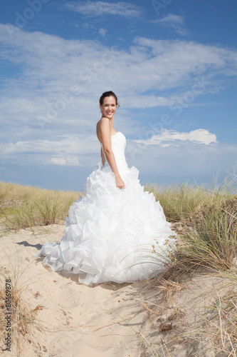 Bride in wedding dress stands on a beach