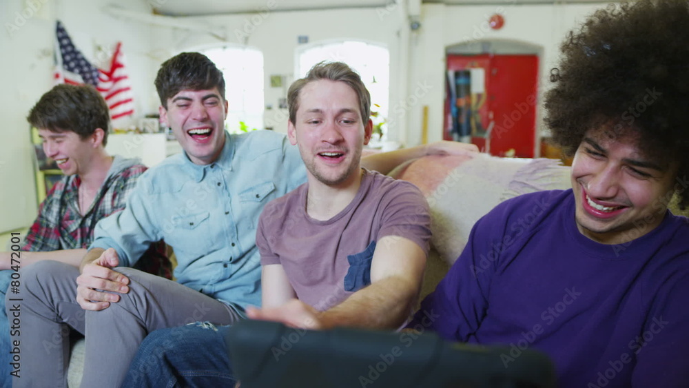 Happy casual group of young male friends relaxing with a tablet computer Happy casual group of young male friends relaxing with a tablet computer