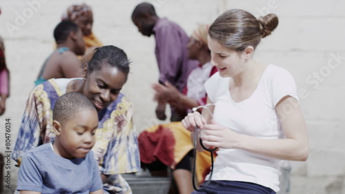 Medical worker from charity organisation uses stethoscope to examine a small boy