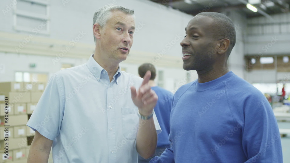 Cheerful factory or warehouse worker taking instruction from the foreman Cheerful factory or warehouse worker taking instruction from the foreman