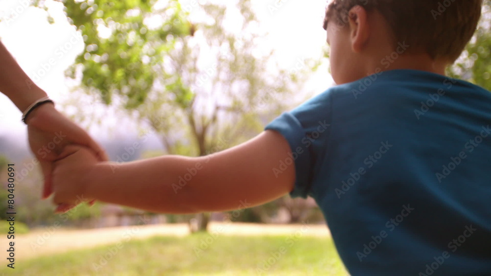 Boy running holding hands with mother in slow motion Boy running holding hands with mother in slow motion