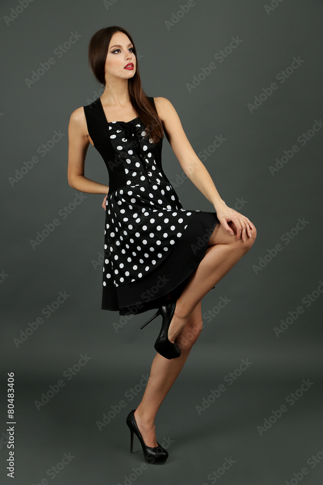 Beautiful young woman in dots dress on dark gray background Beautiful young woman in dots dress on dark gray background