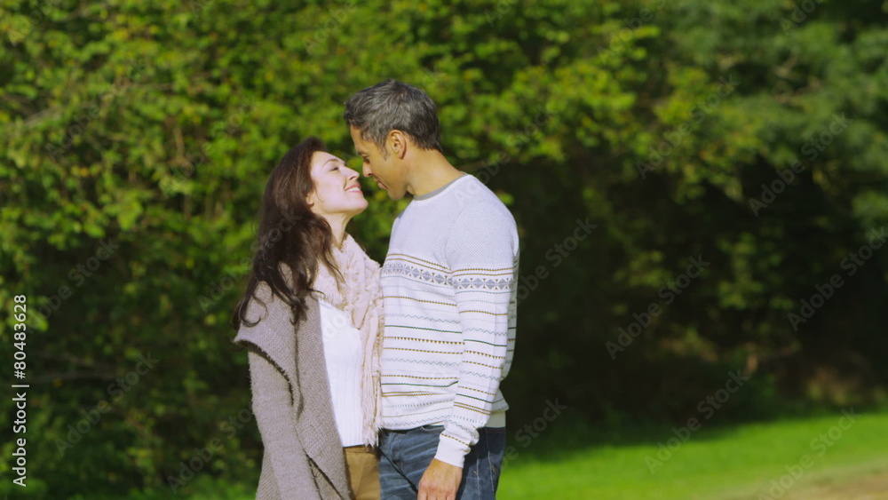 Happy romantic couple walking in the countryside stop for a kiss Happy romantic couple walking in the countryside stop for a kiss